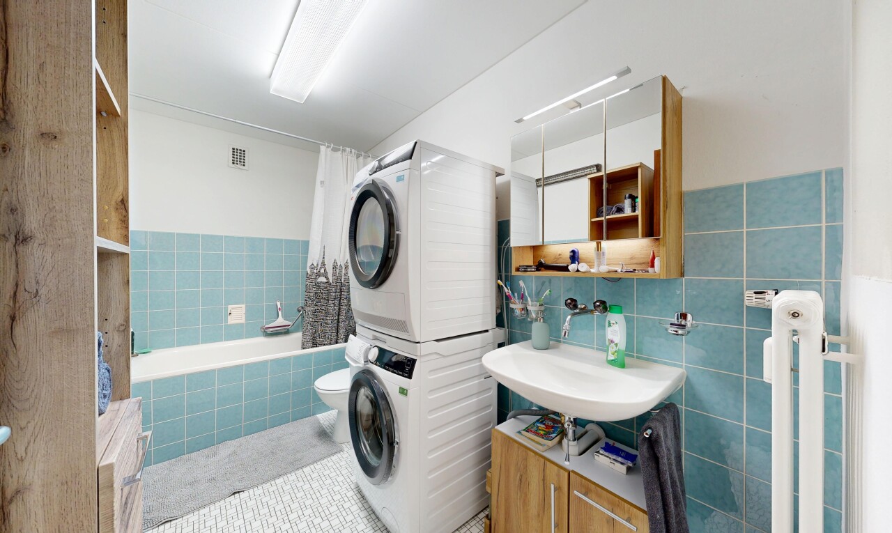 bathroom featuring tiled shower / bath, stacked washer / drying machine, vanity, tile walls, and light tile patterned flooring