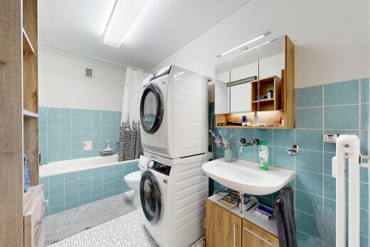 salle de bains avec miroir, salle de bain complète, douche-bain combinés, lave-linge et sèche-linge superposés, et lavabo (ou coiffeuse selon le contexte)