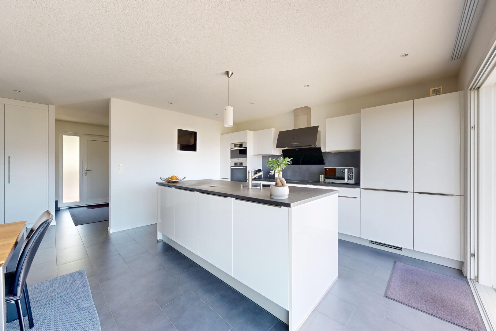 kitchen featuring a center island with sink, white cabinets, dark countertops, stainless steel appliances, and decorative light fixtures