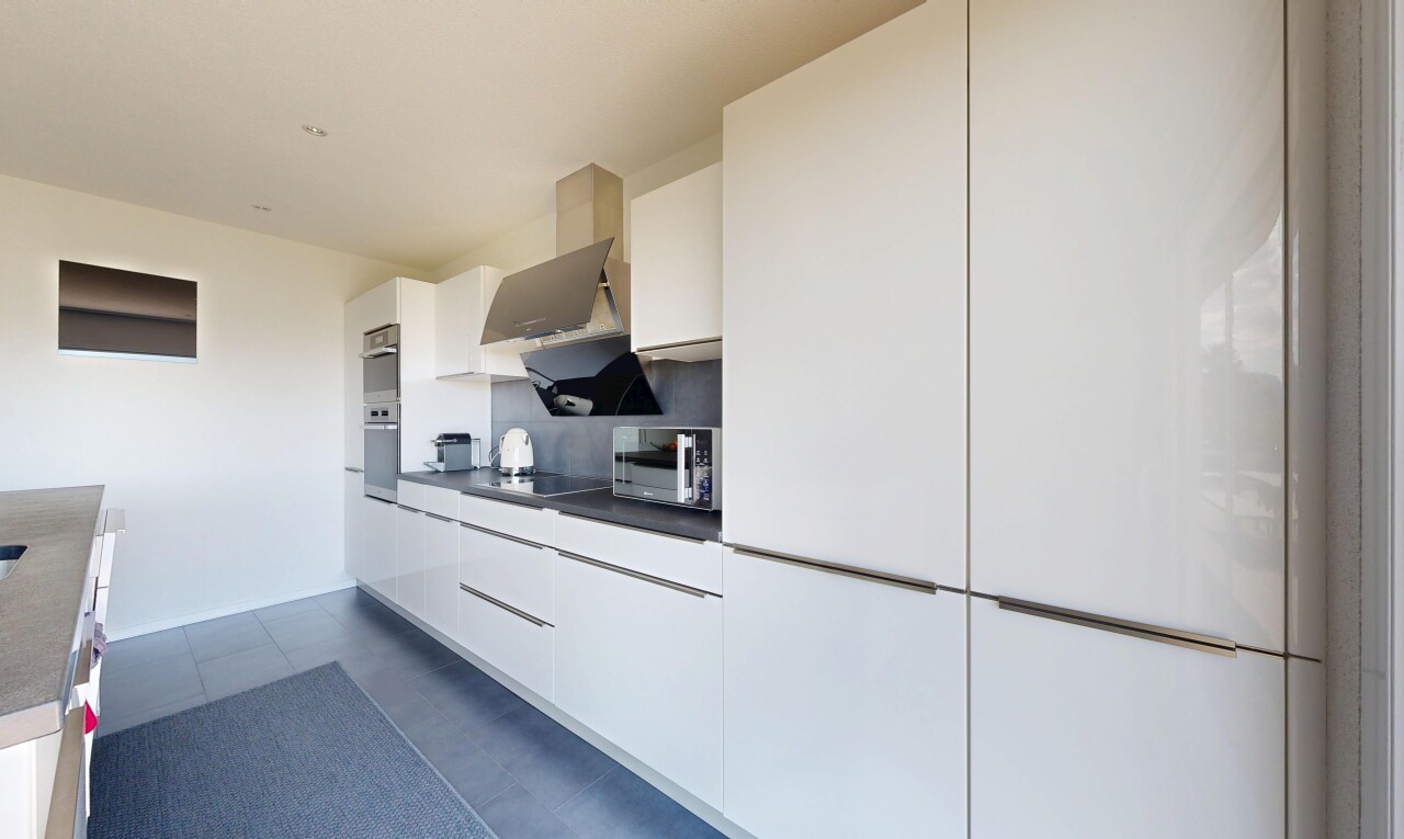 kitchen featuring white cabinetry, dark countertops, modern cabinets, stainless steel microwave, and black electric stovetop