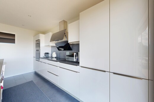 küche mit white cabinets, weiße schränke, dunstabzugshaube, dark floor, und dark countertops