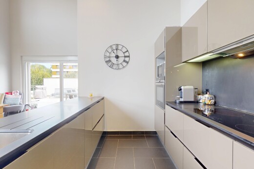 cuisine avec cloison sèche, drywall, armoires à panneau plat, sol en carrelage, et tile floor