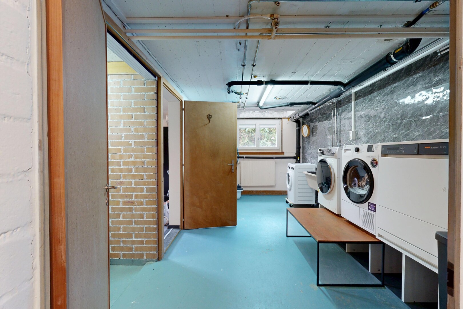 wäschekammer mit natürliches licht, tumbler, finished concrete floor, concrete floor, und keller