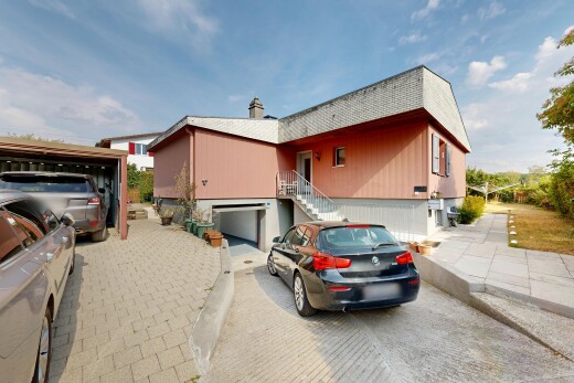 view of home featuring driveway, an attached garage, and a chimney
