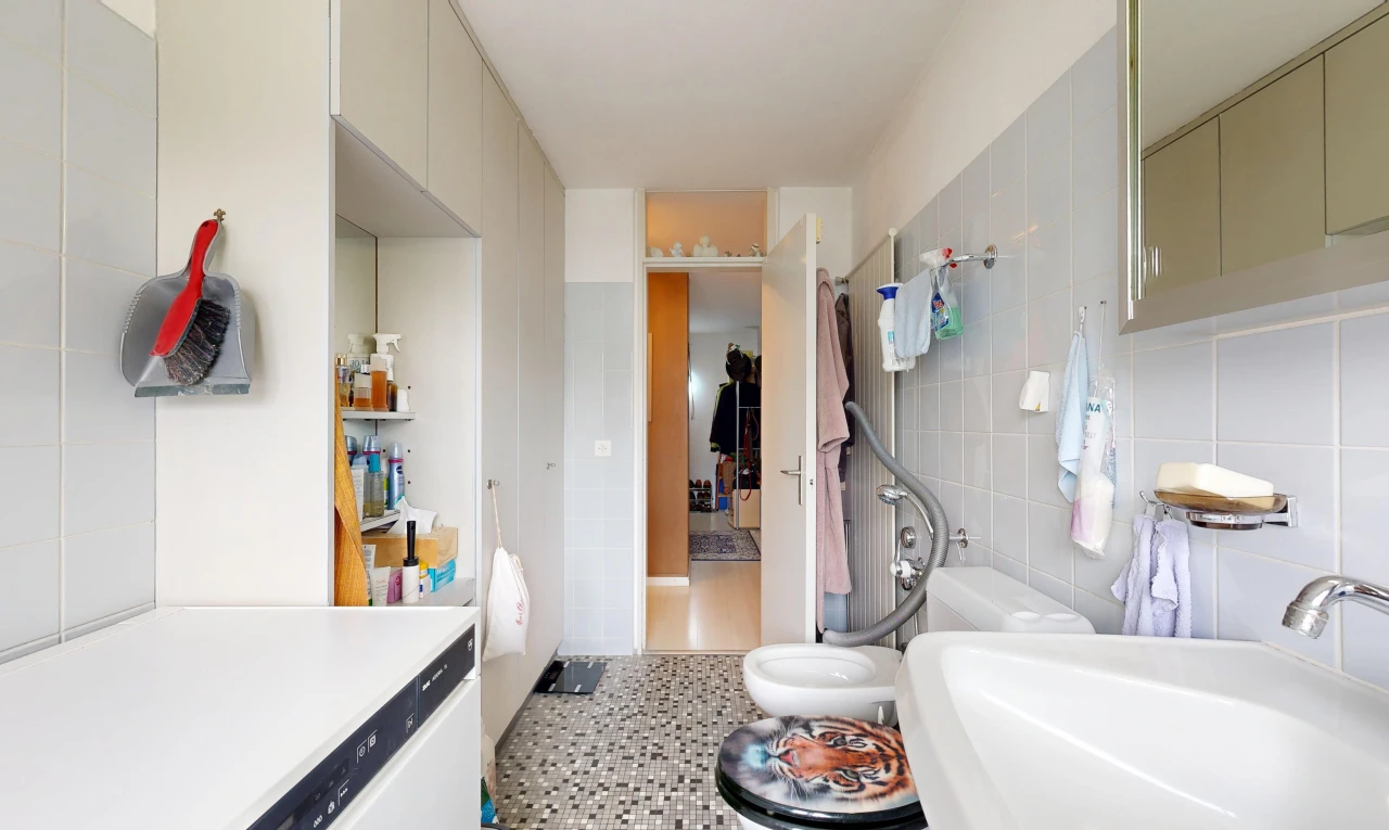 salle de bains avec évier, tile wall, mur en carrelage, light floor, et miroir