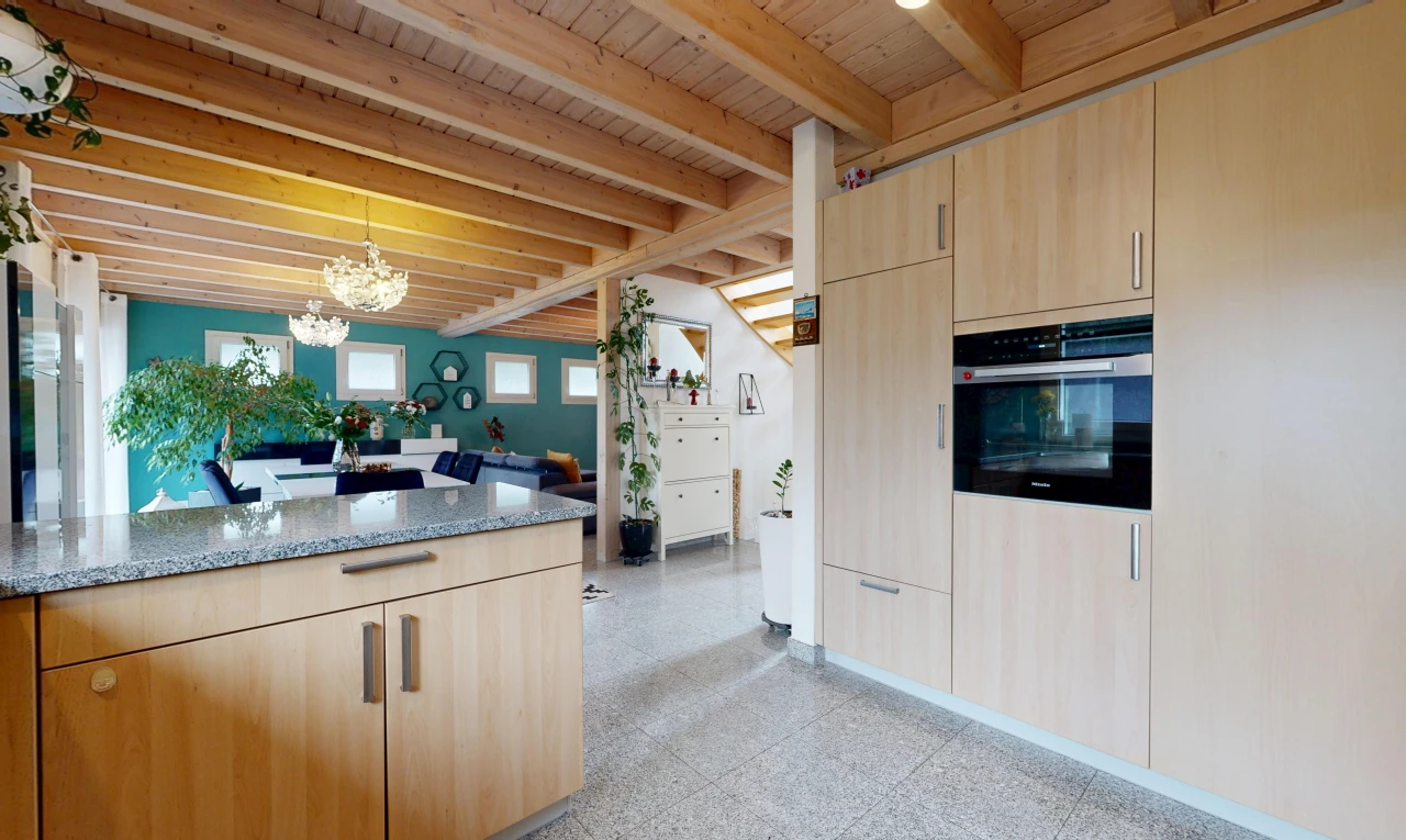 cuisine avec light brown cabinets, armoires marron clair, stone countertops, plans de travail en pierre, et beamed ceiling
