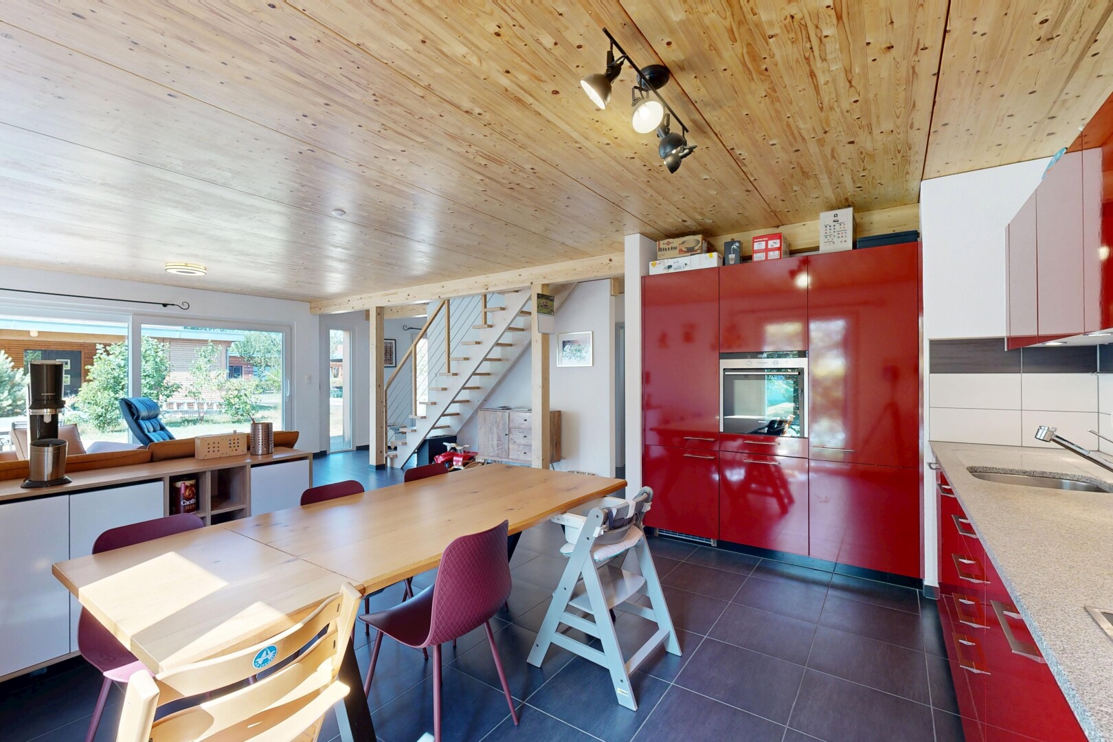 salle à manger avec dark floor, escaliers, wood ceiling, plafond en bois, et évier