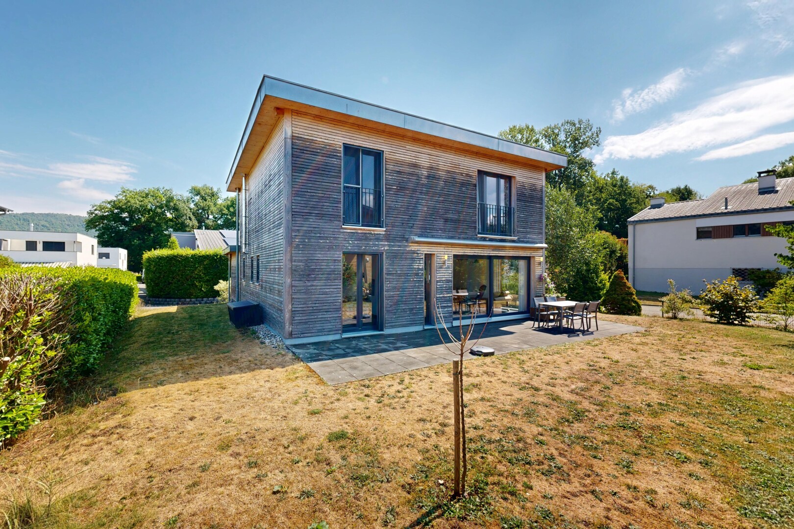 façade avec bardage horizontal, pelouse, terrasse, property visible, et day time