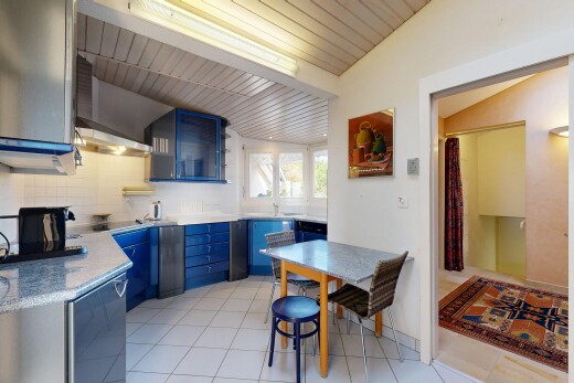 kitchen featuring wall chimney exhaust hood, tasteful backsplash, light tile patterned floors, blue cabinetry, and lofted ceiling