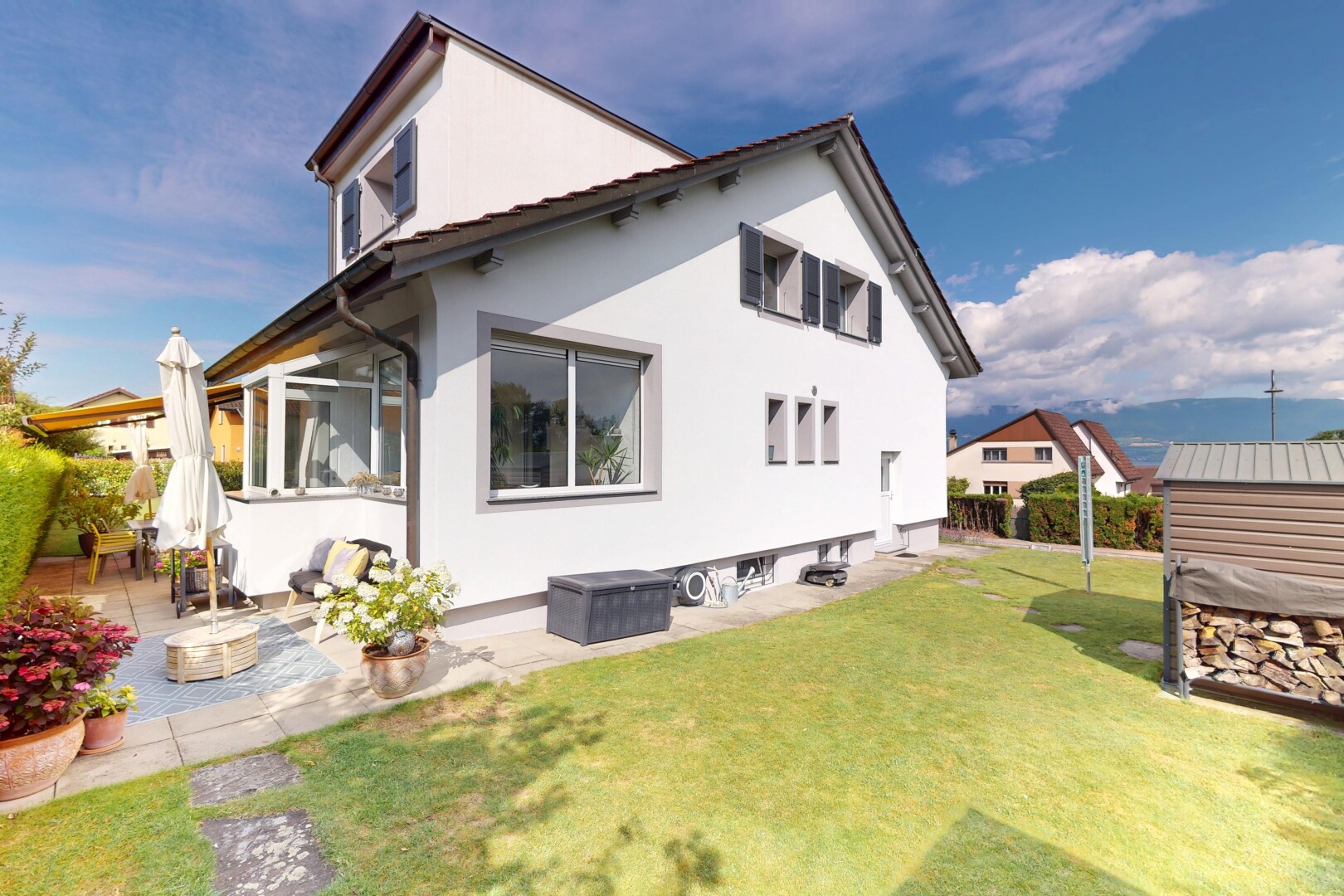 façade avec property visible, terrasse, bardage en stuc, pelouse, et day time