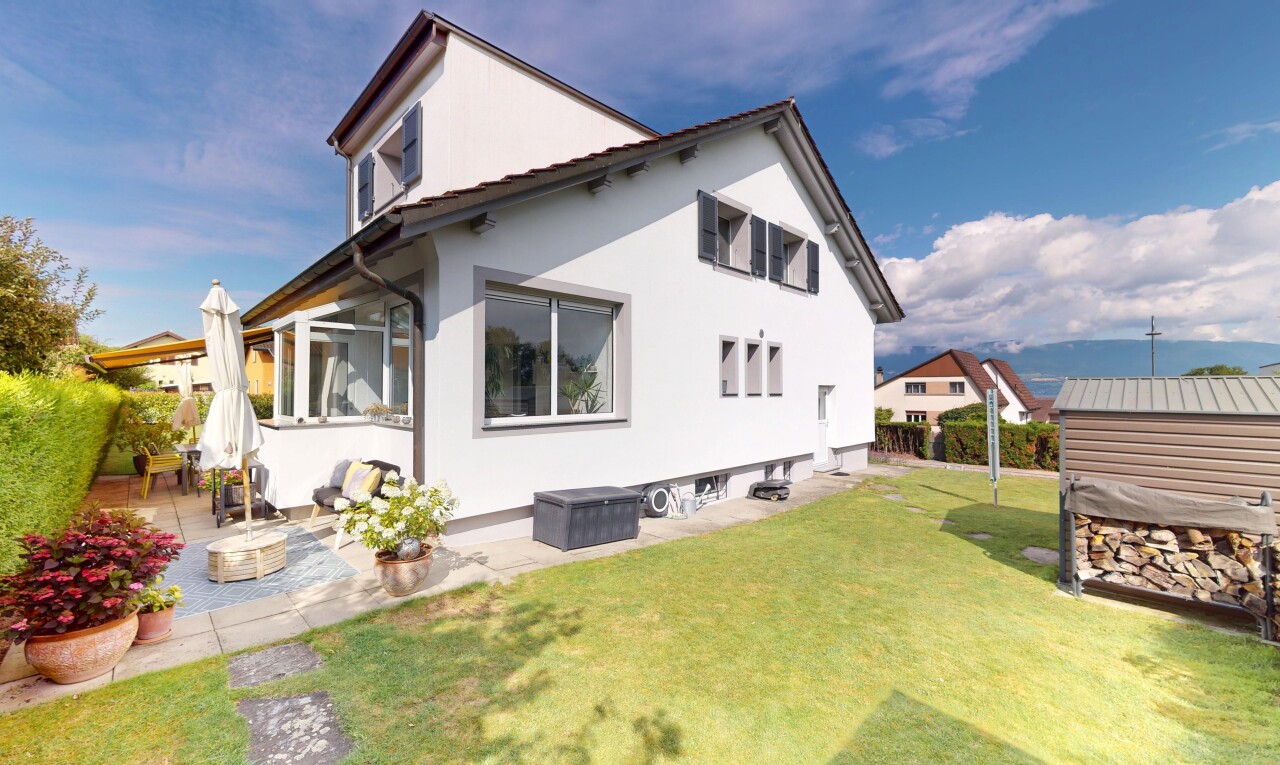 façade avec property visible, terrasse, bardage en stuc, pelouse, et day time