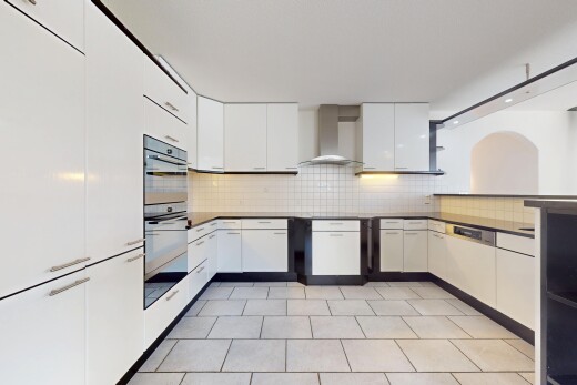 küche mit arbeitsplatten, weiße schränke, doppel backofen, küchenrückwand beim herd, und dunstabzugshaube