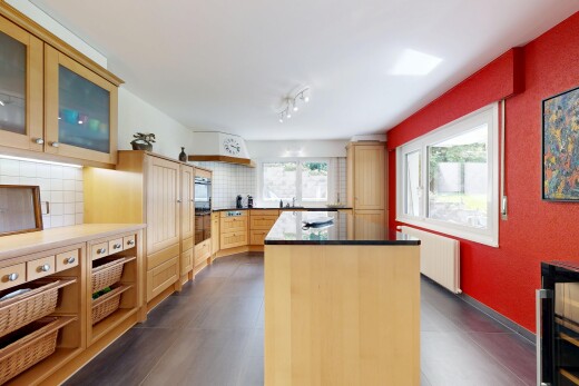 cuisine avec armoires avec insert en verre, îlot de cuisine, dosseret, backsplash, et radiateur