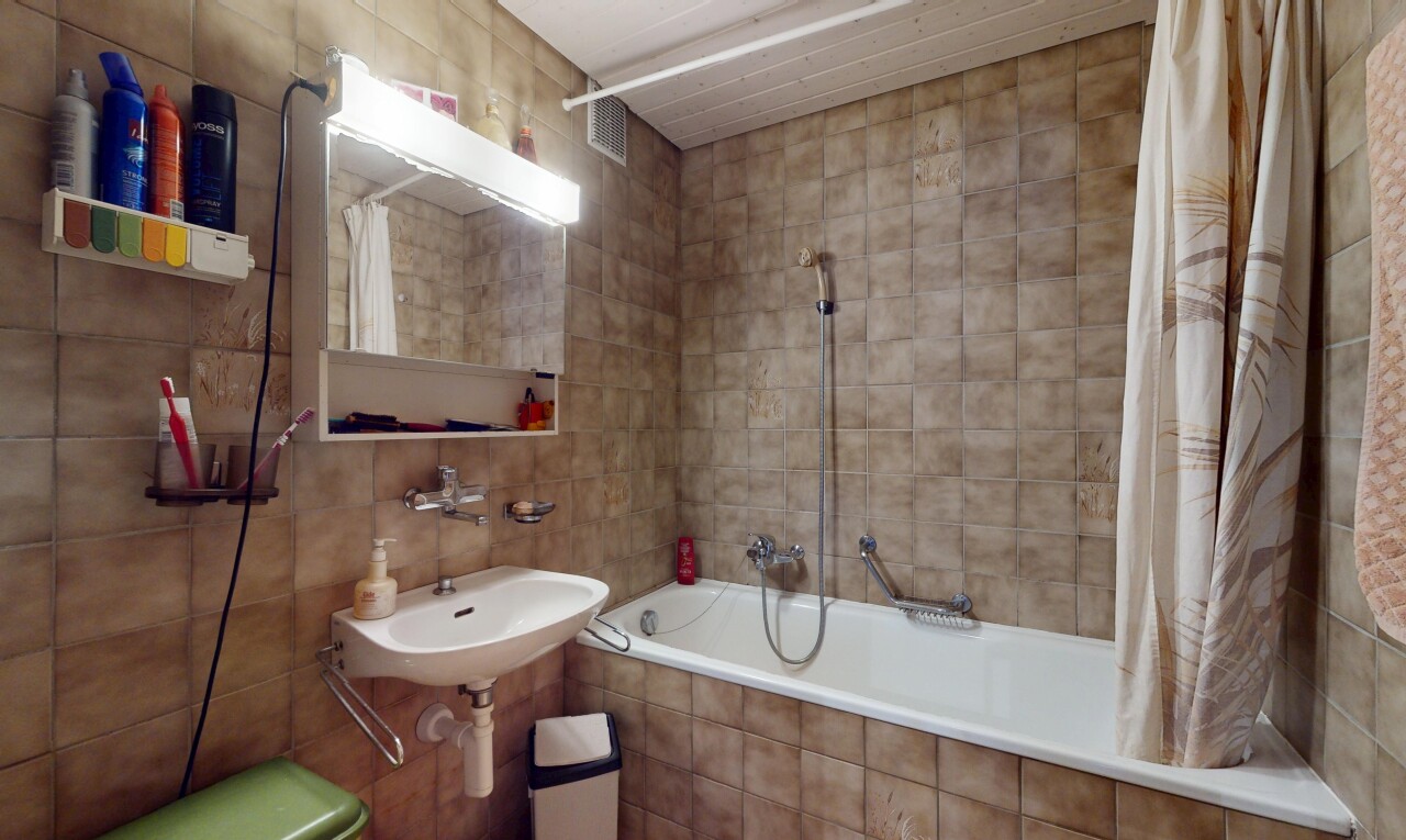 salle de bains avec mur en carrelage, douche-bain combinés, évier, salle de bain complète, et miroir