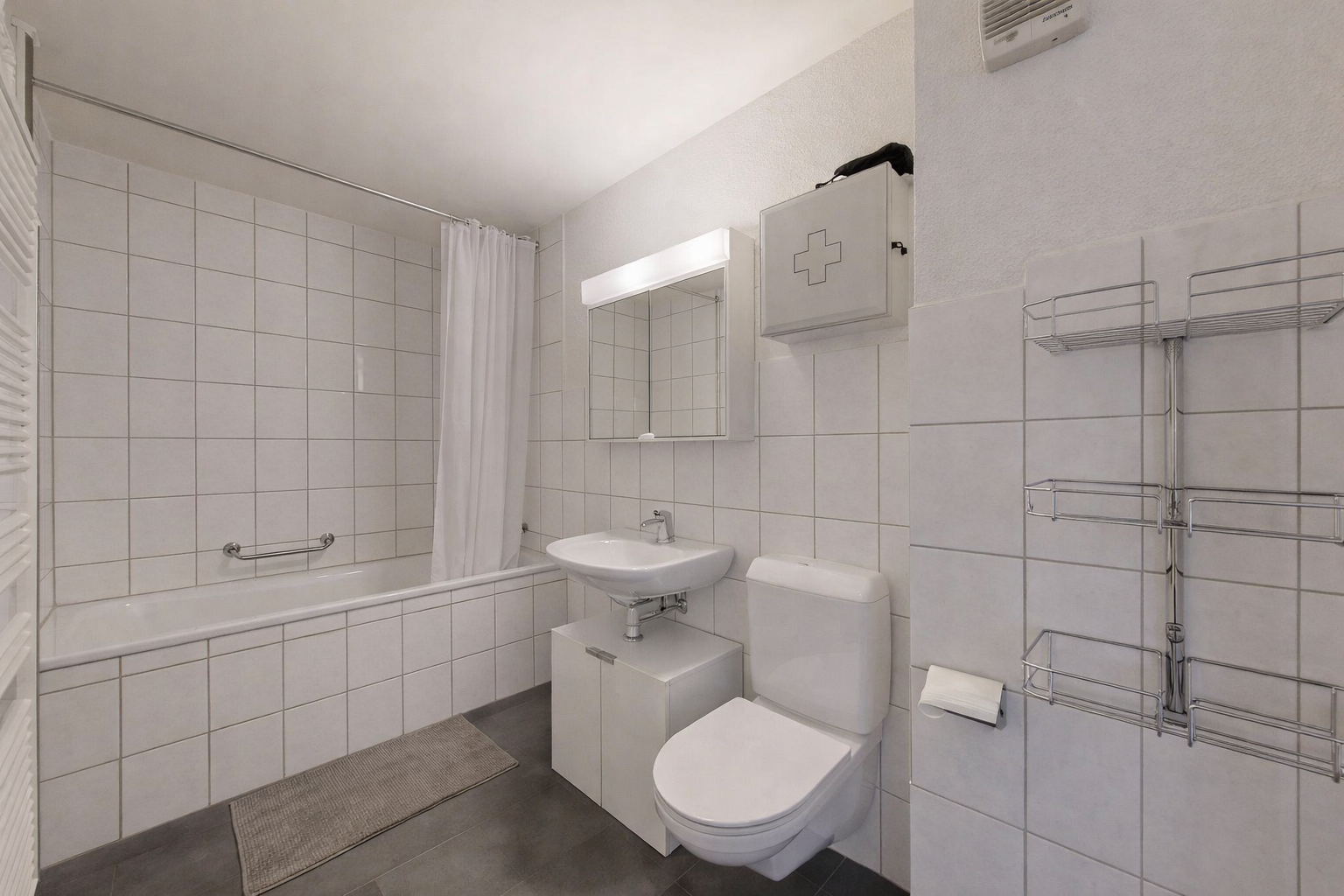 bathroom featuring tiled shower / bath, dark tile patterned flooring, and tile walls