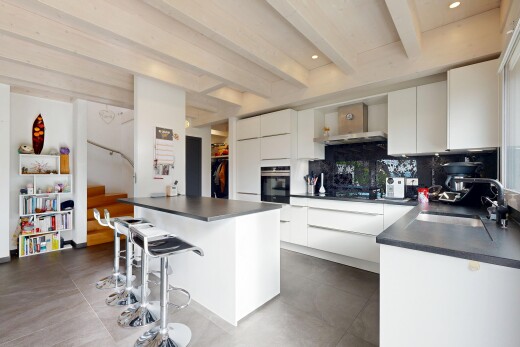 cuisine avec plans de travail, bar de cuisine, îlot de cuisine, armoires à panneau plat, et beamed ceiling