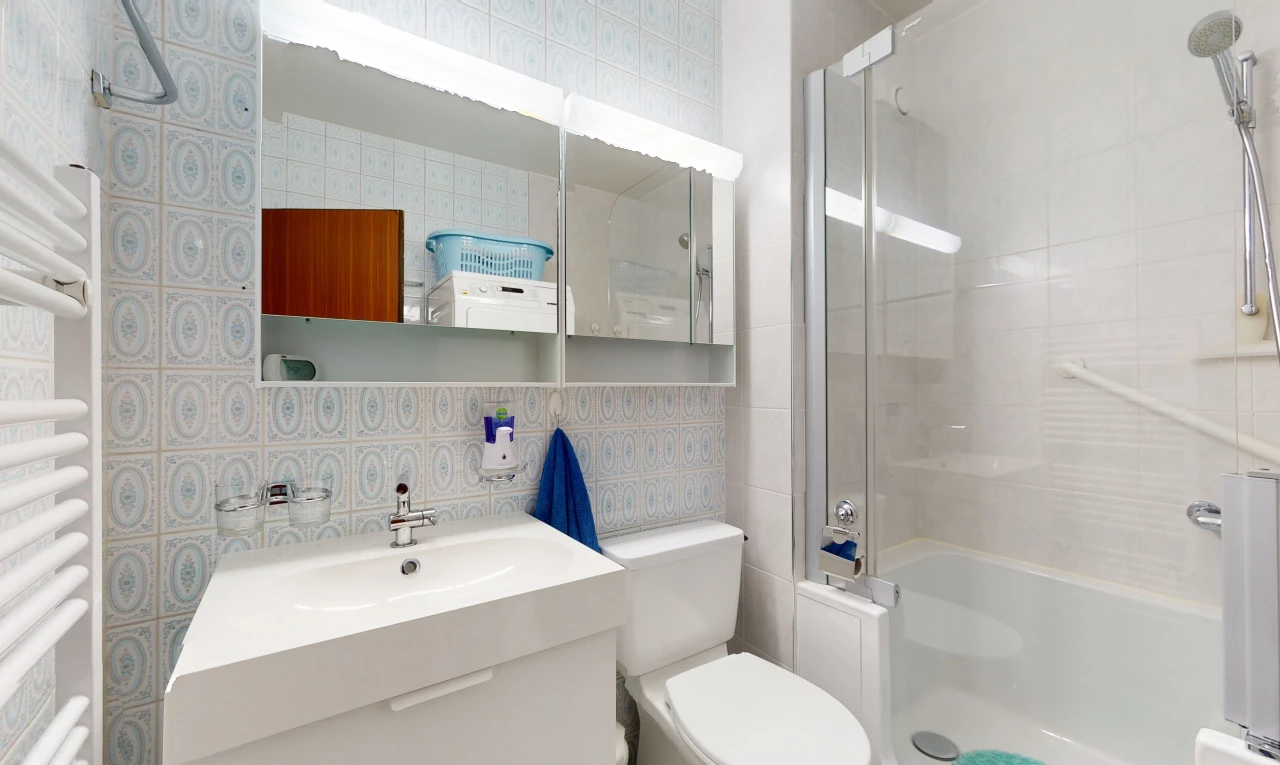 salle de bain avec toilettes, miroir, mur carrelé, meuble-lavabo, et vasque