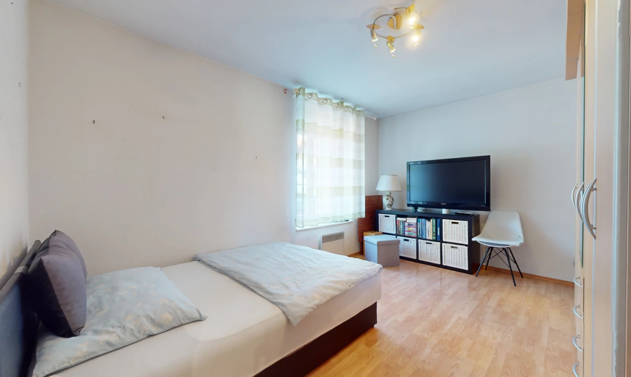 chambre avec télévision, lumière naturelle, et plancher de bois