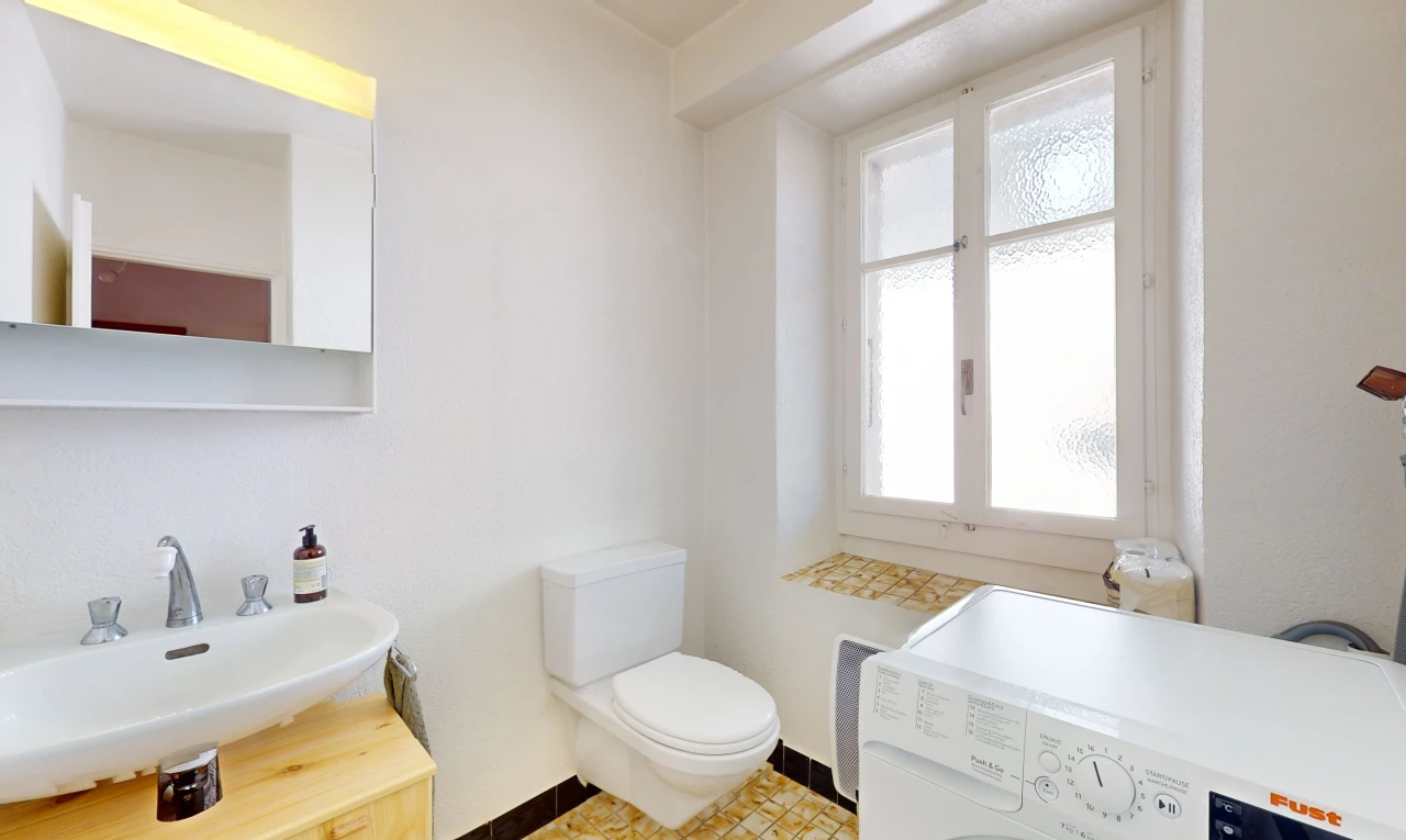 salle de bain avec machine à laver / sèche-linge, miroir, lumière naturelle, vasque, et carrelage