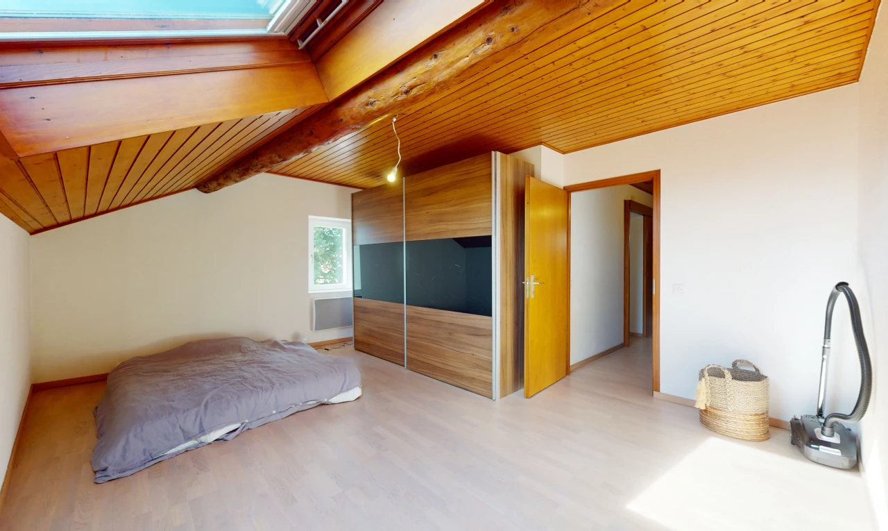 chambre avec plafond voûté, poutres apparentes, plancher de bois, plafond de bois, et lumière naturelle