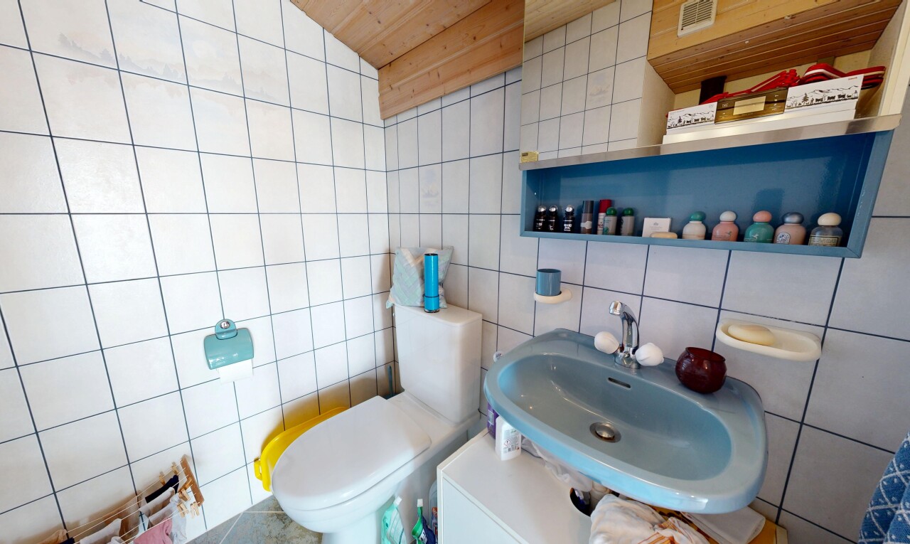 salle de bains avec mur en carrelage, tile wall, toilette, évier, et inside property