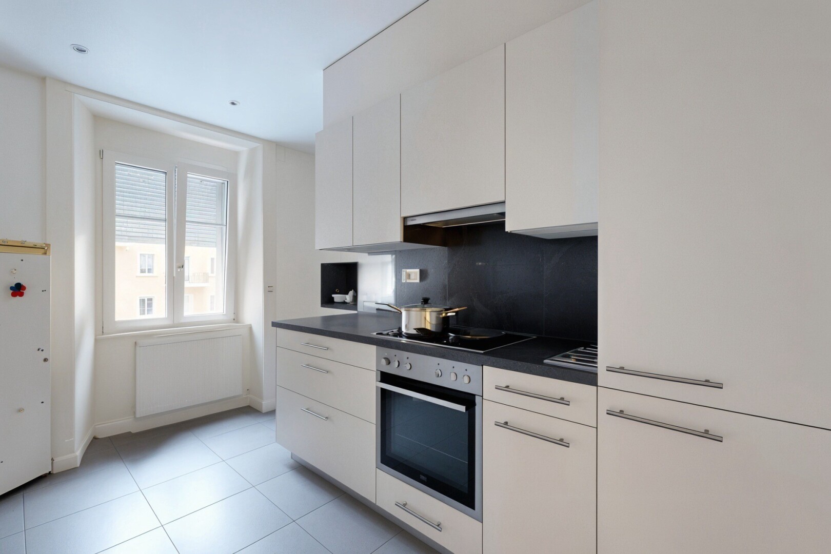 kitchen with dark countertops, white cabinetry, oven, freestanding refrigerator, and decorative backsplash