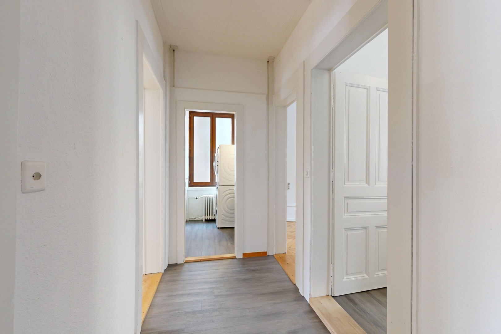 corridor with wood finished floors and radiator heating unit