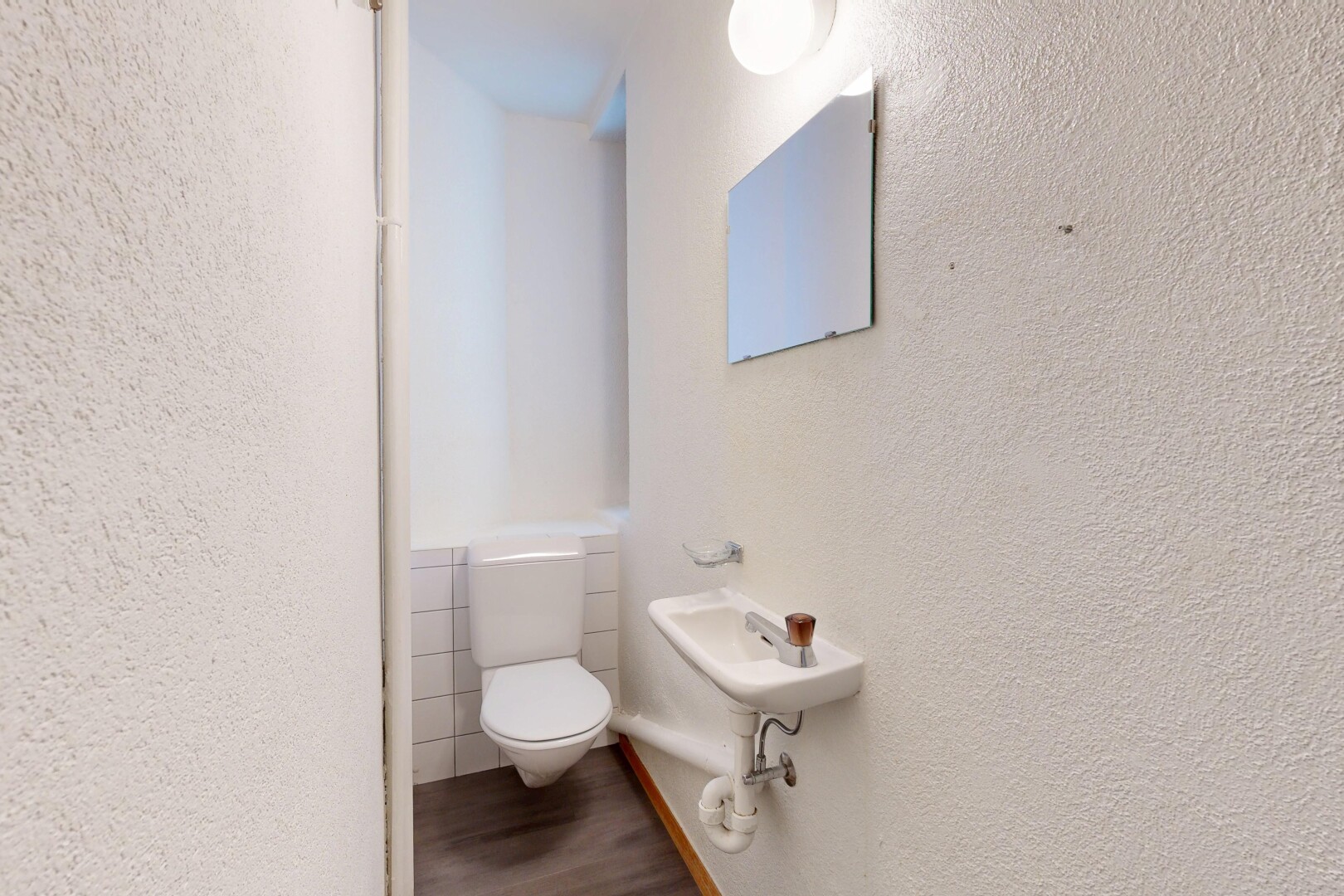bathroom featuring a textured wall and dark wood finished floors