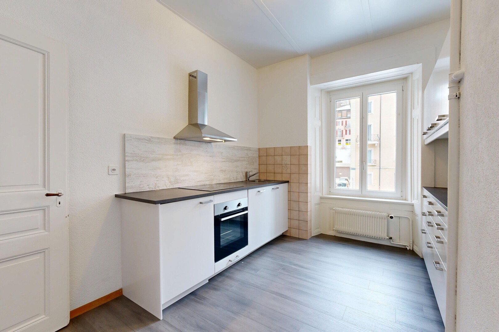kitchen featuring wall chimney range hood, stainless steel oven, white cabinets, radiator heating unit, and light wood finished floors