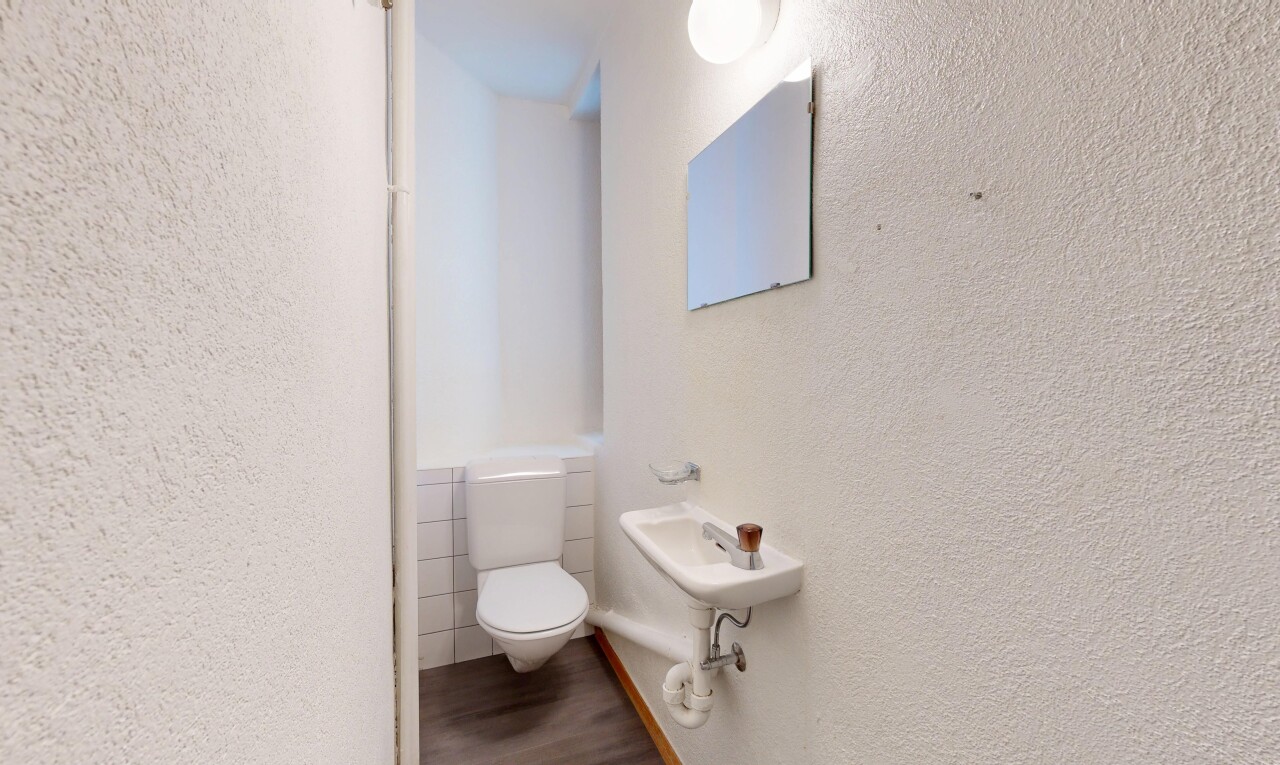 bathroom featuring a textured wall and dark wood finished floors