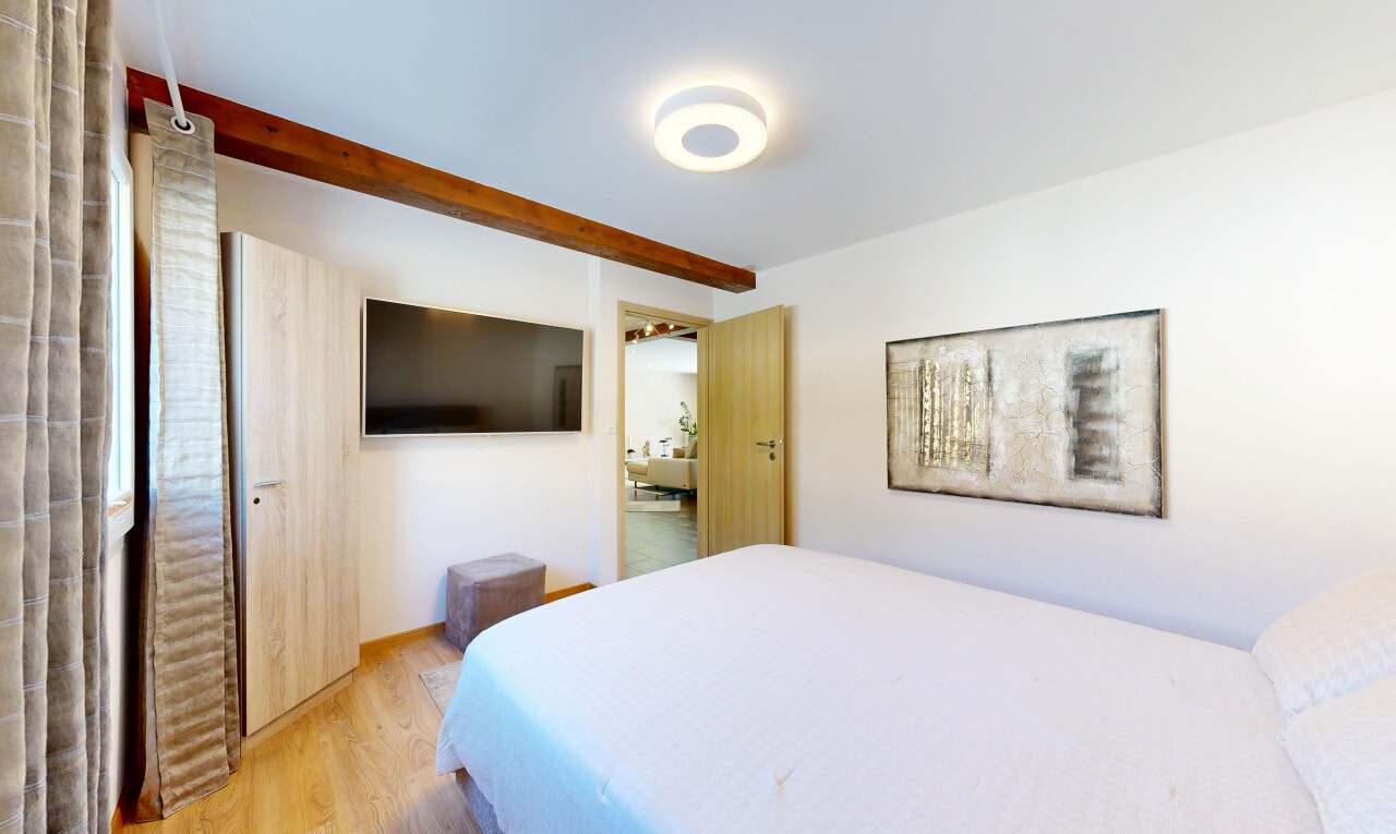 chambre avec télévision, wood finish floor, sol en finition bois, drywall, et cloison sèche