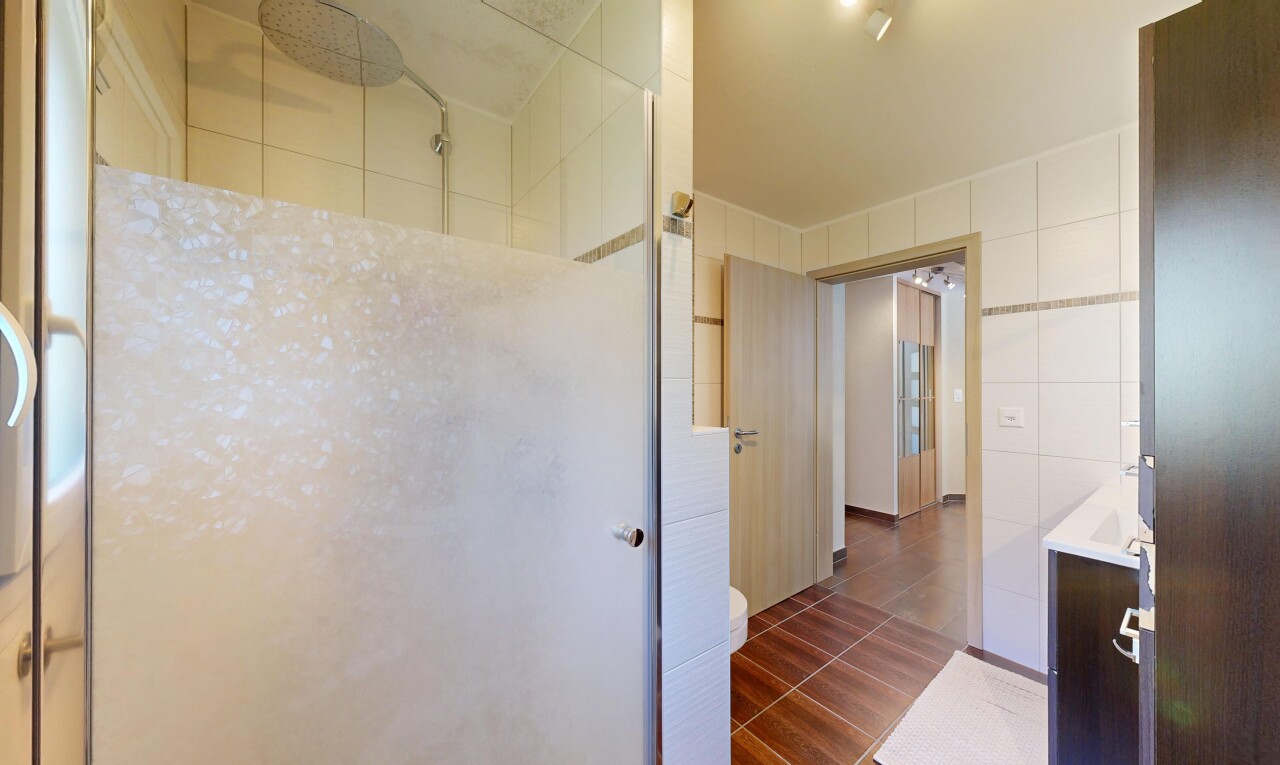 salle de bains avec douche, salle de bain complète, tile wall, dark floor, et inside property