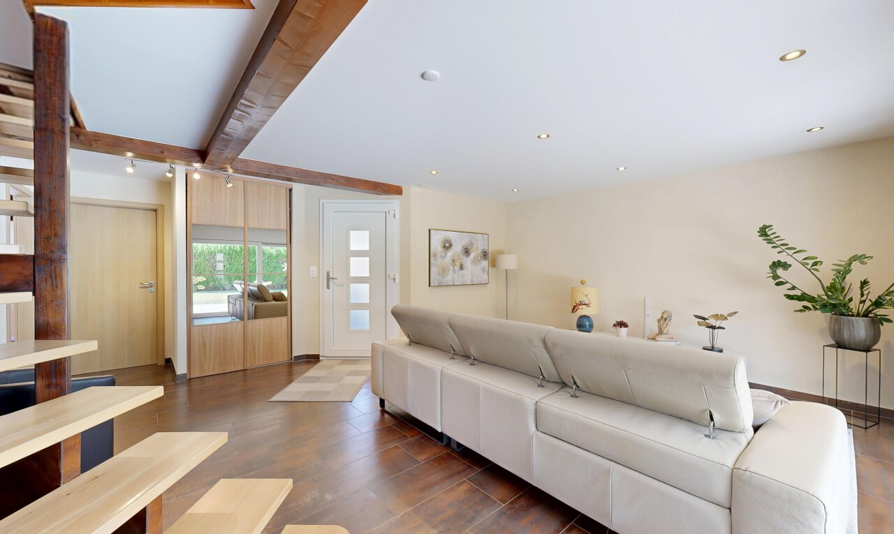 salon avec wood finish floor, sol en finition bois, éclairage sur rail, drywall, et cloison sèche