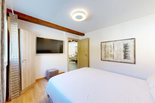 zimmer / schlafzimmer mit fernseher, wood finish floor, holzfußboden, drywall, und gipskartonwand
