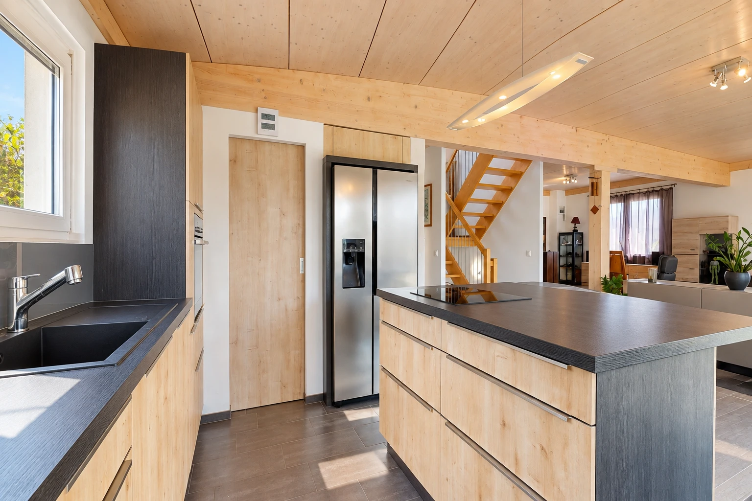 cuisine avec dark countertops, plans de travail, éclairage sur rail, light brown cabinets, et armoires marron clair