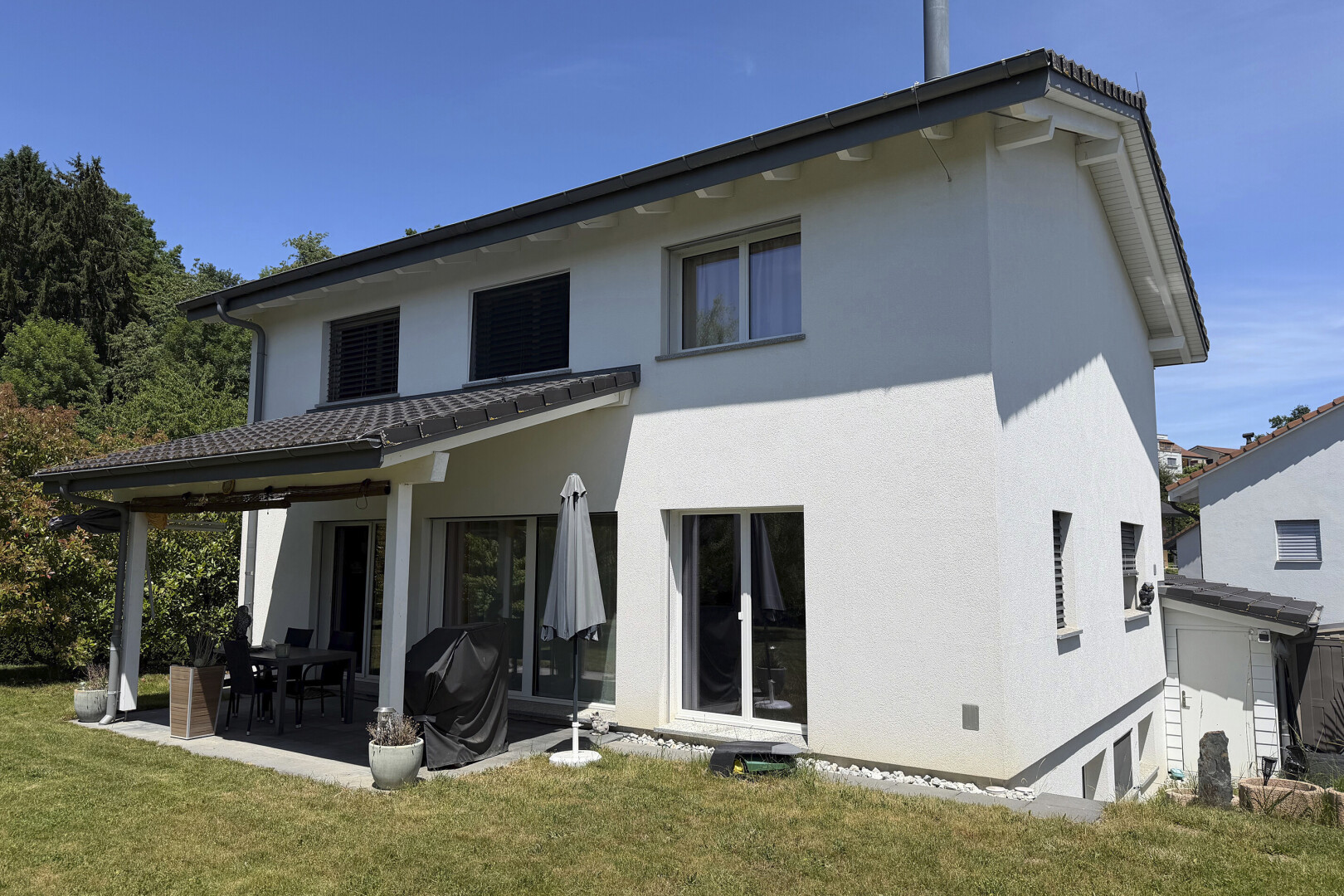 façade avec day time, bardage en stuc, terrasse, pelouse, et property visible