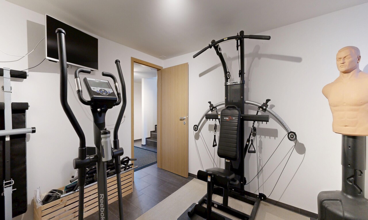 gym avec télévision, cloison sèche, drywall, sol en finition bois, et wood finish floor