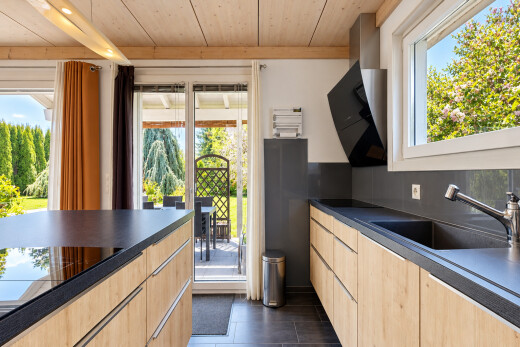 kitchen with dark countertops, light wood finish cabinets, wood ceiling, black electric cooktop, and access to outside