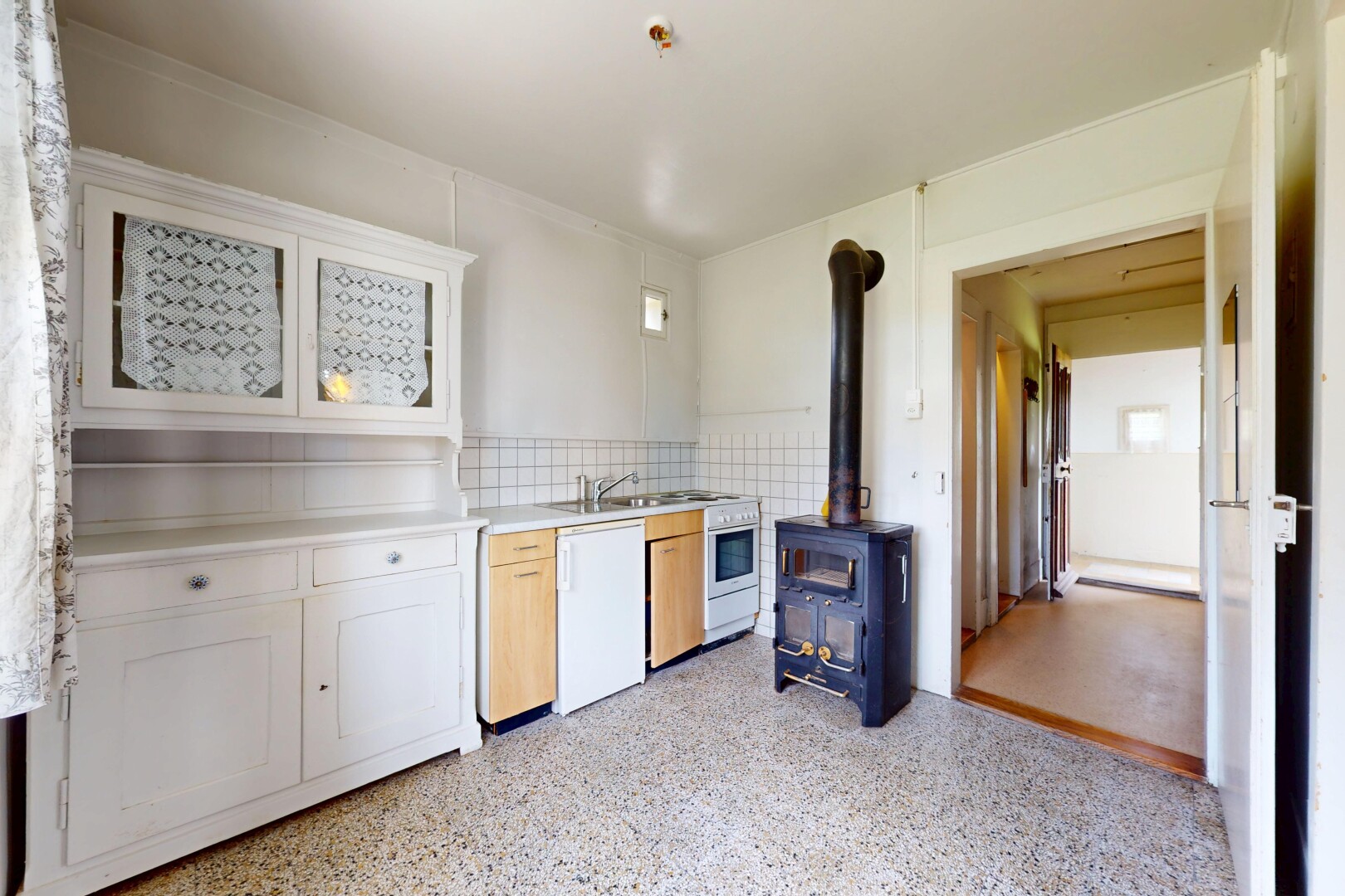 cuisine avec lave-vaisselle, plans de travail, poêle à bois, armoires de style shaker, et inside property