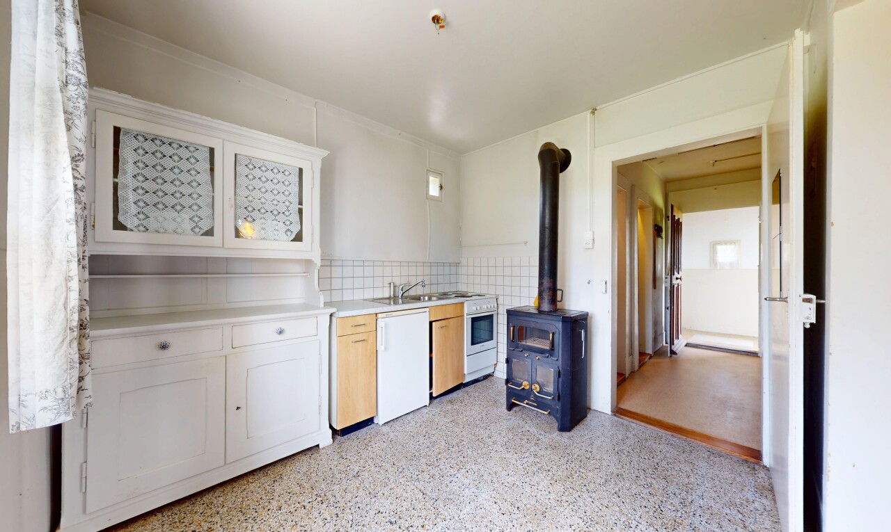 cuisine avec lave-vaisselle, plans de travail, poêle à bois, armoires de style shaker, et inside property