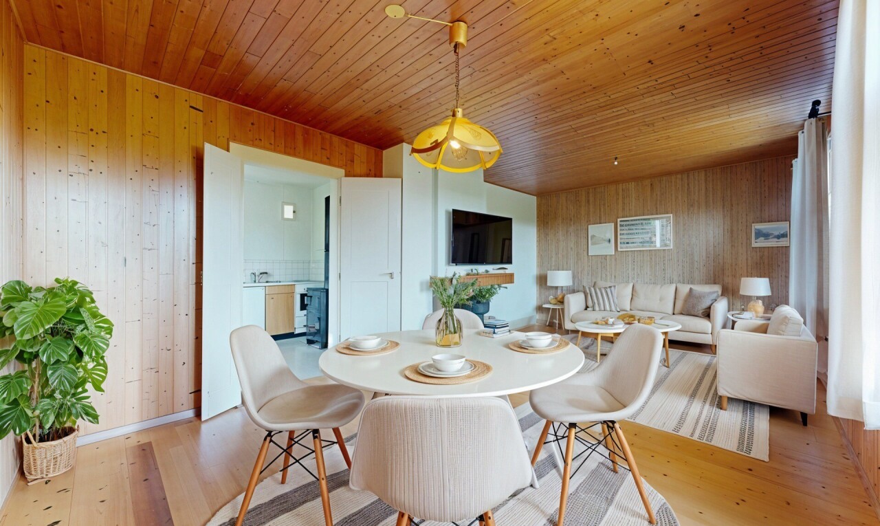 salon / salle à manger avec télévision, mur en bois, wood wall, inside property, et sol en finition bois