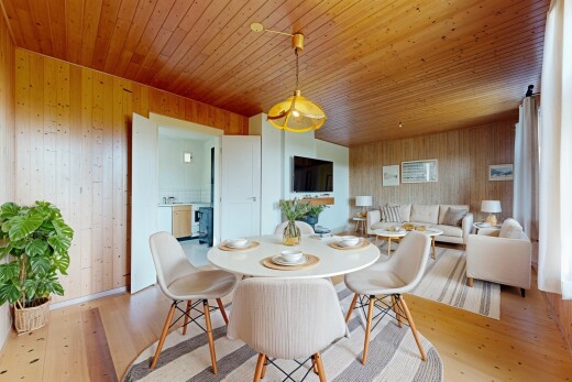 salon / salle à manger avec télévision, mur en bois, wood wall, inside property, et sol en finition bois