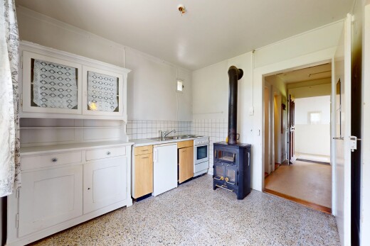 cuisine avec lave-vaisselle, plans de travail, poêle à bois, armoires de style shaker, et inside property