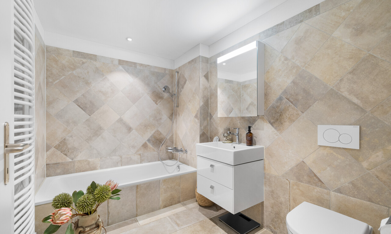 bad mit fliesenwand, kühler, toilette, waschbecken, und kombiniertes bad / dusche