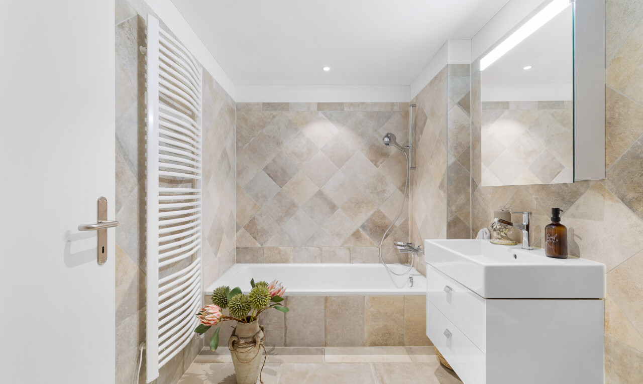 bad mit spiegel, schminktisch, fliesenwand, handtuchwärmer, und kombiniertes bad / dusche