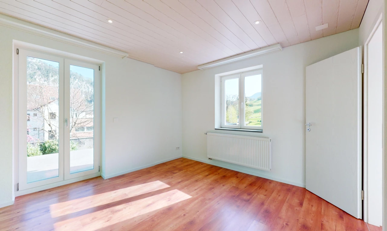pièce vide avec lumière naturelle, plancher de bois, et radiateur