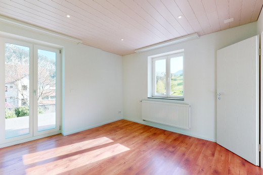 pièce vide avec lumière naturelle, plancher de bois, et radiateur