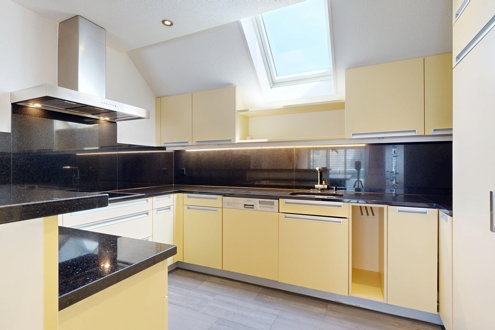 küche mit dunstabzugshaube, cream cabinets, cremefarbene schränke, dark countertops, und light floor