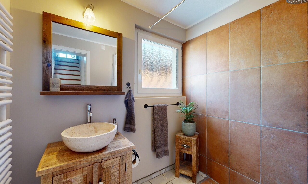 bad mit spiegel, schminktisch, waschbecken, inside property, und natürliches licht