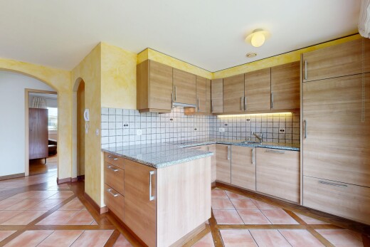 kitchen featuring inlaid floor details, light brown cabinets, decorative backsplash, and light stone countertops